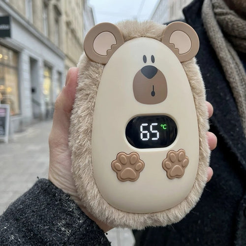 CozyPuff oso beige sujetado en la mano en una calle en invierno, con la pantalla marcando 65 grados