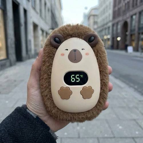 CozyPuff oso marrón sujetado en la mano en una calle en invierno, con la pantalla marcando 65 grados